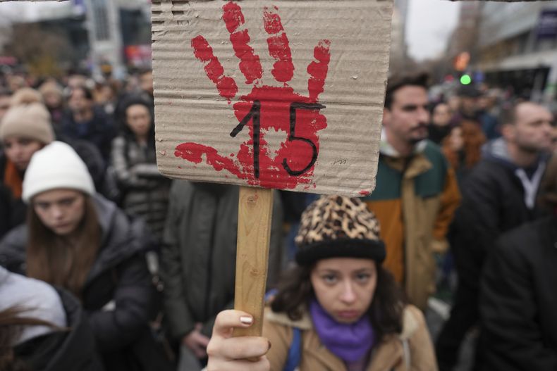 Gente detiene el tráfico y guarda silencio en una protesta en memoria por los 15 muertos de un derrumbe en una estación seis semanas antes, para reclamar responsabilidades por la tragedia, en Belgrado, Serbia., el viernes 13 de diciembre de 2024. (AP Foto/Darko Vojinovic)
