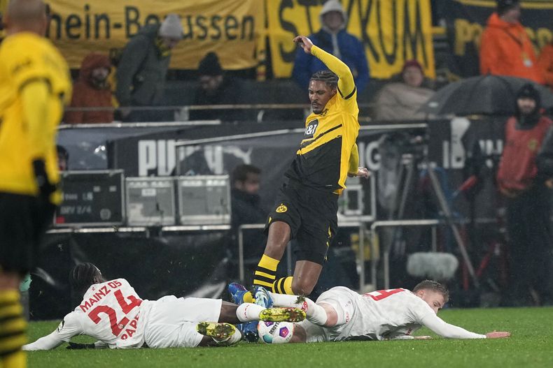 Sebastien Haller, centro, del Dortmund, pelea el balón con Merveille Papela, izquierda, y un compañero de Mainz, durante el partido de fútbol de la Bundesliga de entre Borussia Dortmund y FSV Mainz 05 en el Signal-Iduna Park, en Dortmund, Alemania, el martes 29 de diciembre de 2023. (AP Foto/Martin Meissner)