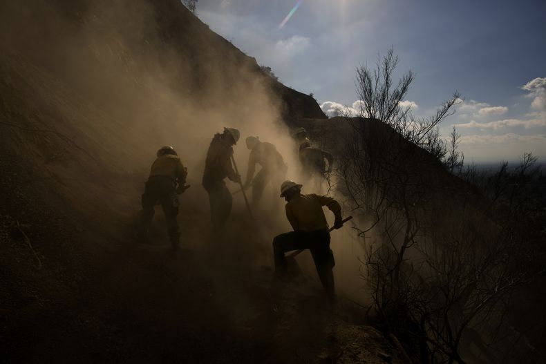 Miembros del equipos de bomberos Navajo Scouts levantan polvo al retirar los restos de un deslave en una colina, mientras trabajan en la extinción del incendio de Eaton, el 17 de enero de 2025, en Altadena, California. (AP Foto/John Locher)