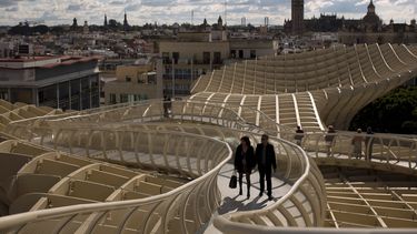 Una pareja camina por uno de los corredores del Metropol Parasol, desde donde se ve la ciudad antigua y la Catedral de Sevilla con La Giralda en España, el 18 de noviembre de 2012. La Academia Latina de la Grabación anunció el 4 de mayo de 2023 que la 24a ceremonia del Latin Grammy se celebrará el 16 de noviembre en esta ciudad del sur de España. (Foto AP/Emilio Morenatti, archivo)