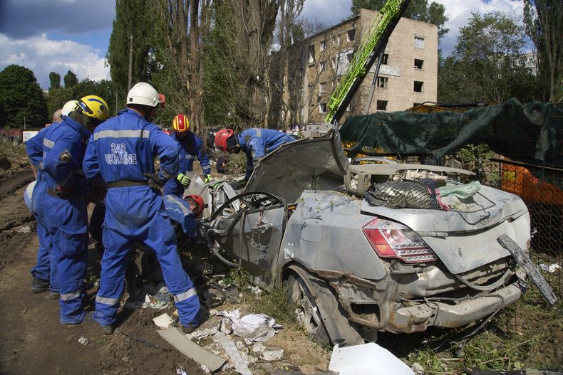 Trabajadores de emergencias inspeccionan un auto dañado cerca de un edificio residencial de varias plantas alcanzado por un misil ruso, en un operativo que dejó 31 muertos, en Kiev, Ucrania, el 1 de agosto de 2025. (AP Foto/Efrem Lukatsky)