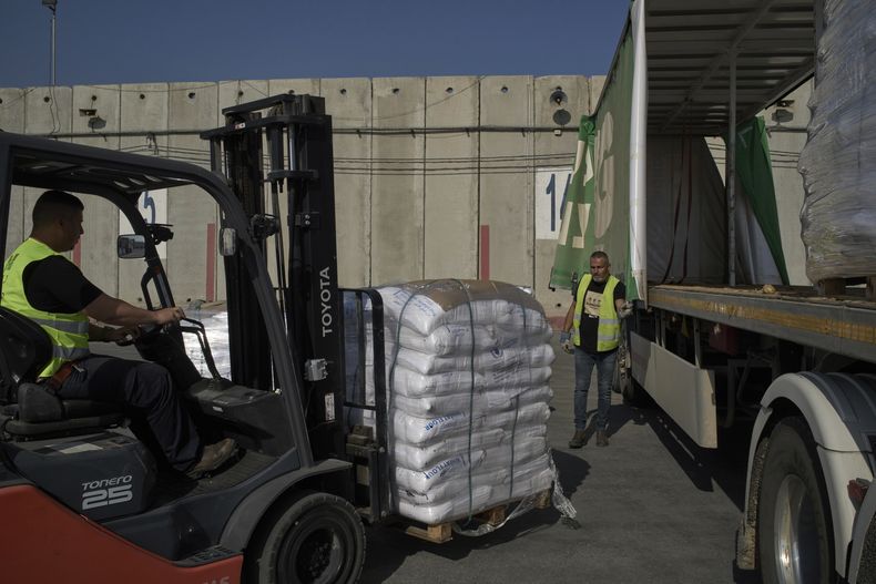 Trabajadores descargan un camión que transporta ayuda humanitaria para la Franja de Gaza en el área de descarga del cruce fronterizo de Kerem Shalom entre Israel y Gaza, en el sur de Israel, el jueves 22 de mayo de 2025. (AP Foto/Leo Correa)