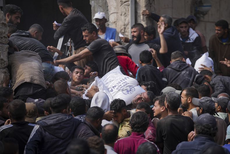 Palestinos se reúnen para recibir bolsas de harina distribuidas por la UNRWA, la agencia de la ONU que ayuda a los refugiados palestinos, en Deir al Balah, en el centro de la Franja de Gaza, el sábado 2 de noviembre de 2024. (AP Foto/Abdel Kareem Hana)