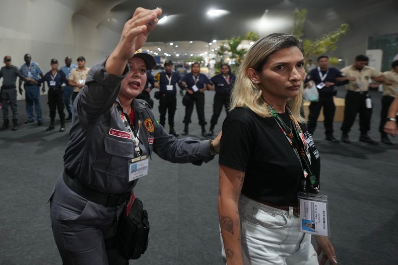 Guardias de seguridad ayudan a la gente a evacuar un edificio usado en la cumbre climática COP30 en Belém, Brasil, el 20 de noviembre del 2025. (AP foto/Andre Penner)
