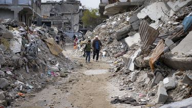 Dos personas caminan entre los escombros de viviendas destruidas por la ofensiva del ejército israelí contra Hamás, el miércoles 19 de febrero de 2025, en Jabaliya, en el norte de la Franja de Gaza. (AP Foto/Abdel Kareem Hana)