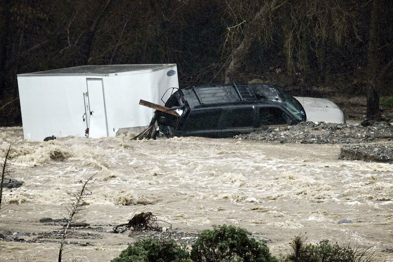 Una camioneta SUV yace en las rocas de la orilla del arroyo Cajon cerca de Devore, California, el lunes 5 de febrero de 2024, luego de que fue arrastrado por las inundaciones provocadas por las fuertes lluvias que han azotado el estado. (Watchara Phomicinda/The Orange County Register via AP)