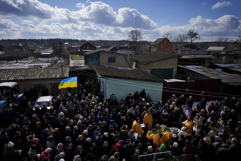 Personas se reúnen junto al cadáver de Vladyslav Bondarenko, de 26 años, durante su funeral en Kozyntsi, cerca de Kiev, Ucrania, el lunes 6 de marzo de 2023. Bondarenko, un paracaidista de una brigada aérea, murió cerca de Bájmut el 26 de febrero de 2023. (AP Foto/Thibault Camus)