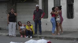 Varias personas lloran junto al cadáver de un hombre, asesinado en circunstancias desconocidas, en una calle de Durán, Ecuador, el 21 de julio de 2023, en medio de una ola de violencia que las autoridades atribuyen a la lucha de territorio entre bandas del crimen organizado. (AP Foto/Dolores Ochoa)