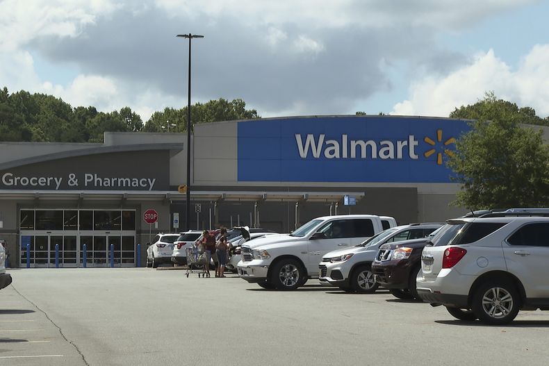 En esta imagen tomada de un video, compradores suben sus compras a un vehículo el lunes 31 de julio de 2023, en un Walmart de Lincolnton, Carolina del Norte, en donde la policía asegura que trabajadores migrantes fueron atropellados intencionalmente por una camioneta en el estacionamiento de la tienda un día antes. (AP Foto/Erik Verduzco)