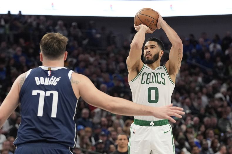 Jayson Tatum (0), de los Celtics de Boston, dispara ante la mirada de Luka Doncic (77), de los Mavericks de Dallas, durante la segunda mitad del juego de baloncesto de la NBA en Dallas, el lunes 22 de enero de 2024. (AP Foto/LM Otero)