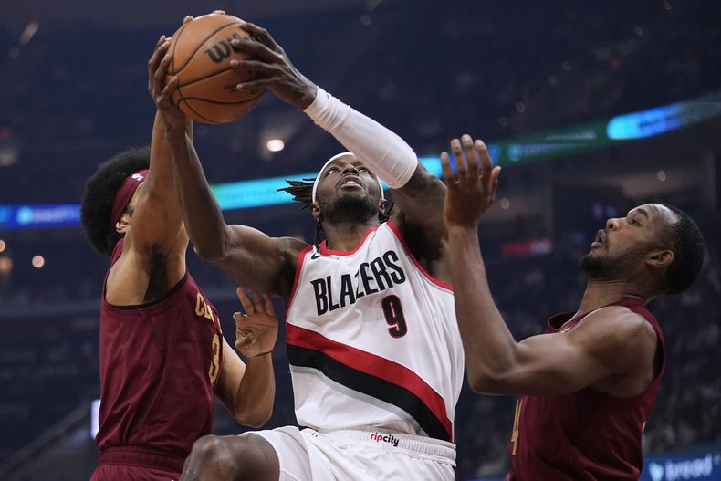 El alero de los Trail Blazers de Portland Jerami Grant avanza hacia la canasta superando a Jarrett Allen y Evan Mobley de los Cavaliers de Cleveland en el encuentro del lunes 30 de noviembre del 2023. (AP Foto/Sue Ogrocki)