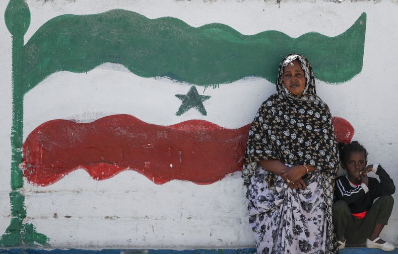 ARCHIVO - Una mujer y un niño descansan en un muro que la bandera de Somalilania, en Hargeisa, Somalilandia, un territorio semiautónomo, el 9 de febrero de 2022. (AP Foto/Brian Inganga, archivo)