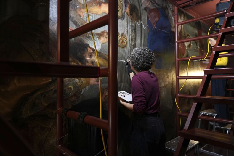 Las restauradoras de arte Jill Keppens, izquierda, y Kayla Metelenis, derecha, trabajan bajo un andamio en secciones de Madona entronizada con niño, rodeada de santos, pintada por el artista flamenco Peter Paul Rubens, en el Museo Real de Bellas Artes de Amberes, Bélgica, el miércoles 15 de enero de 2025 (Foto AP/Virginia Mayo)