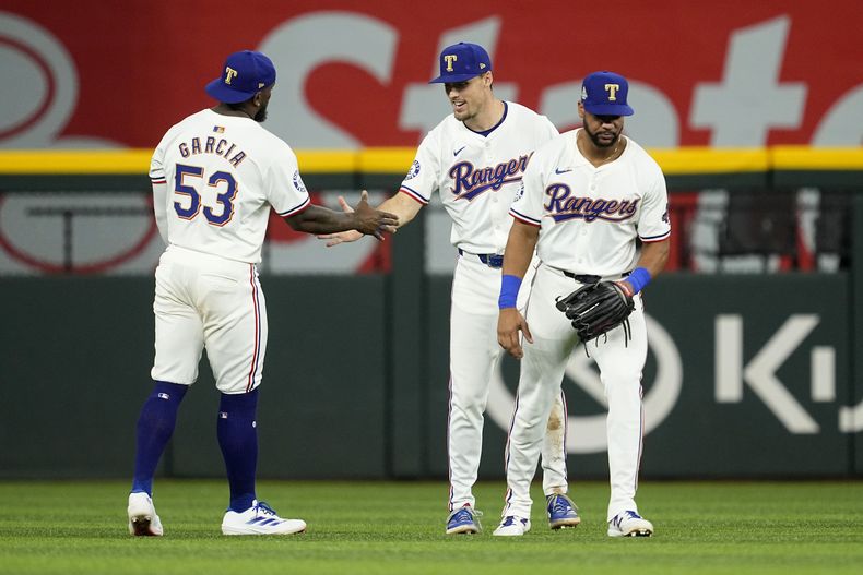 El cubano Adolis García, Evan Carter y el dominicano Leody Taveras, de los Rangers de Texas, se felicitan por el triunfo sobre los Atléticos de Oakland, el miércoles 10 de abril de 2024 (AP Foto/Tony Gutiérrez)