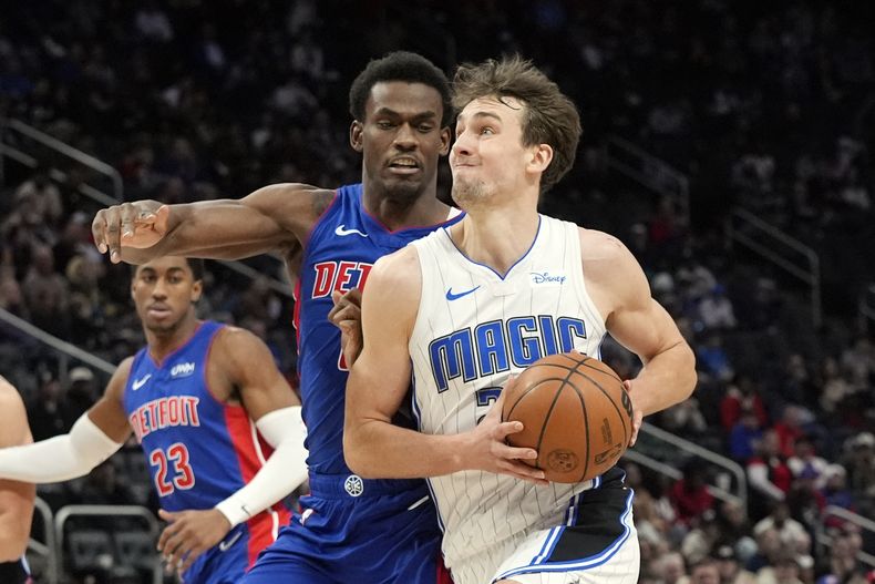 El alero del Magic de Orlando Franz Wagner avanza hacia la canasta mientras lo persigue el pívot de los Pistons de Detroit Jalen Duren en el encuentro de la NBA el domingo 4 de febrero del 2024. (AP Foto/Carlos Osorio)