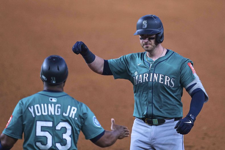 Mitch Garver, derecha, de los Marineros de Seattle, celebra con el coach de primera base Eric Young Jr. (53) después de pegar un sencillo productor de carrera en la sexta entrada del juego de béisbol de Grandes Ligas frente a los Rangers de Texas, el domingo 29 de junio de 2025, en Arlington, Texas. (AP Foto/Tony Gutierrez)