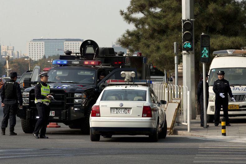 Dos polic&iacute;as (derecha) y miembros de un equipo policial de respuesta r&aacute;pida custodian una calle donde el lunes un veh&iacute;culo se encim&oacute; sobre una multitud cerca de la Plaza de Tiananmen, donde se estrell&oacute; y se incendi&oacut