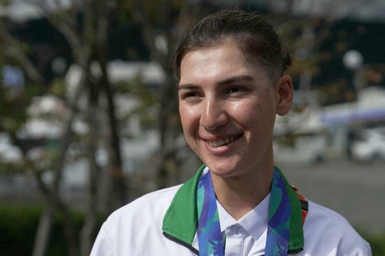 En esta imagen extraida de un video, la afgana Fariba Hashimi, quien ganó la medalla de plata en el ciclismo de ruta de los Juegos Asiáticos, charla con The Associated Press en Shinshiro, Japón, el miércoles 23 de septiembre de 2026. (SNTV vía AP)