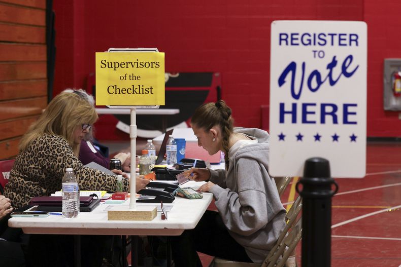 La supervisora de la lista de control del estado de Nueva Hampshire Leslie Dombroski, a la izquierda, inscribe a Elise Collins, de 18 años, para votar en Derry, Nueva Hampshire, el martes 11 de marzo de 2025. (AP foto/Reba Saldanha)