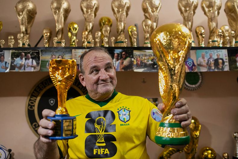 Jarbas Meneghini Carlini posa con las réplicas de los trofeos de la Copa del Mundo de la FIFA que realiza en su taller, el viernes 15 de mayo del 2026. (AP Foto/Bruna Prado)