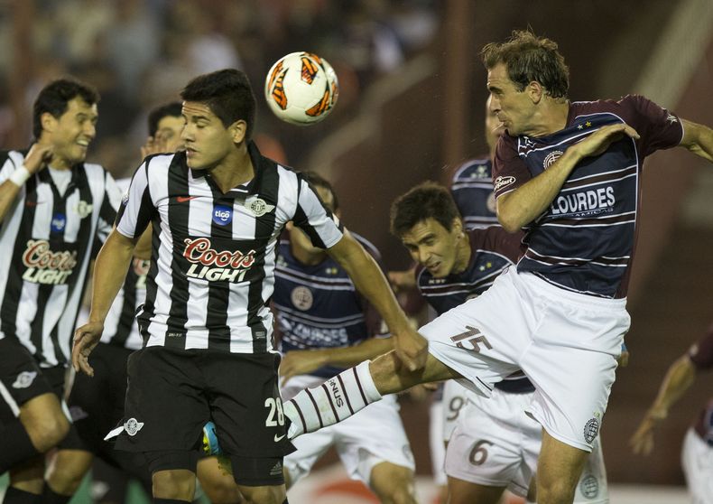 Leandro Somoza, del club argentino Lan&uacute;s, derecha, disputa el bal&oacute;n con Jorge Recalde del Libertad de Paraguay, durante su juego de vuelta de las semifinales de la Copa Sudamericana, el jueves 28 de noviembre de 2013, en Buenos Aires, Argent