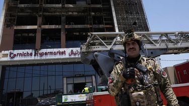 Un guarda de seguridad iraquí hace guardia delante del edificio de un hipermercado incendiado, en Kut, Irak, el 17 de julio de 2025. (AP Foto/Hadi Mizban)