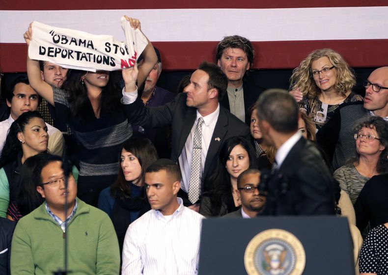 Un hombre le quita un letrero a una mujer que interrumpi&oacute; un discurso del presidente Barack Obama sobre inmigraci&oacute;n despu&eacute;s de que el mandatario se reuni&oacute; con l&iacute;deres comunitarios para hablar sobre las medidas ejecutivas