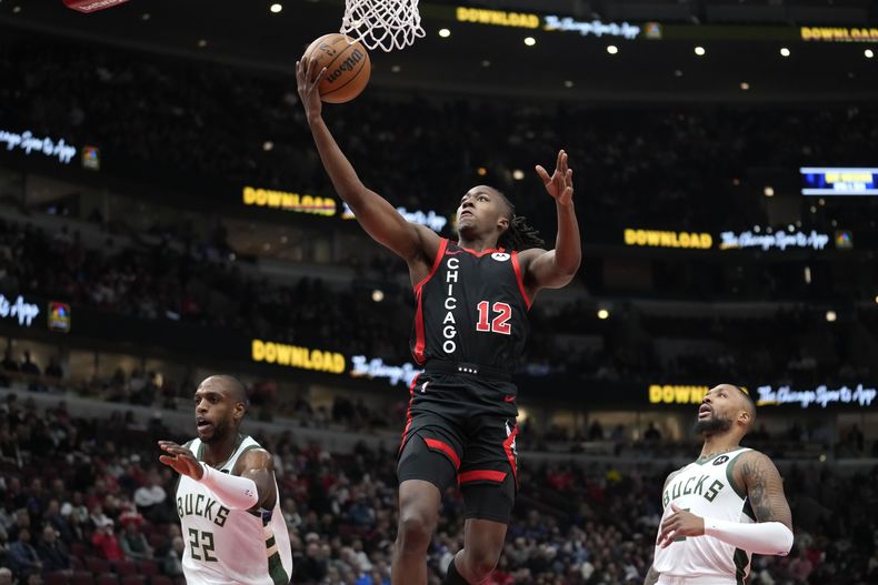 Ayo Dosunmu de los Bulls de Chicago salta hacia la canasta frente a Khris Middleton y Damian Lillard de los Bucks de Milwaukee en el encuentro del jueves 30 de noviembre del 2023. (AP Foto/Charles Rex Arbogast)