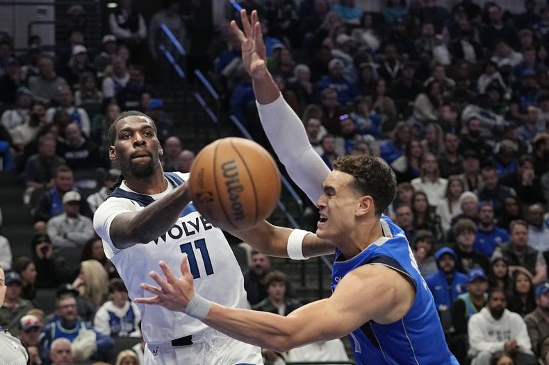 Naz Reid, pívot de los Timberwolves de Minnesota, envía un pase frente a Dwight Powell, de los Mavericks de Dallas, en el encuentro del jueves 14 de diciembre de 2023 (AP Foto/LM Otero)