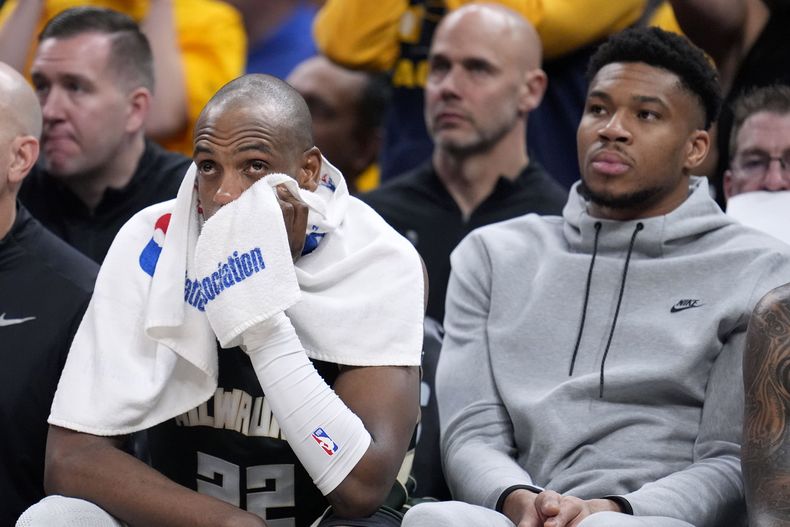 Khris Middleton y Giannis Antetokounmpo, de los Bucks de Milwaukee, observan desde el banquillo el sexto partido de la serie de playoffs ante los Pacers de Indiana, el jueves 2 de mayo de 2024 (AP Foto/Michael Conroy)