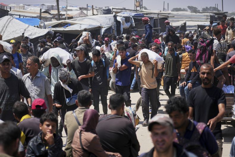 Palestinos cargan bolsas que contienen alimentos y paquetes de ayuda humanitaria entregadas por la Fundación Humanitaria de Gaza, una organización respaldada por Estados Unidos, en Rafah, en el sur de la Franja de Gaza, el domingo 15 de junio de 2025. (AP Foto/Abdel Kareem Hana)