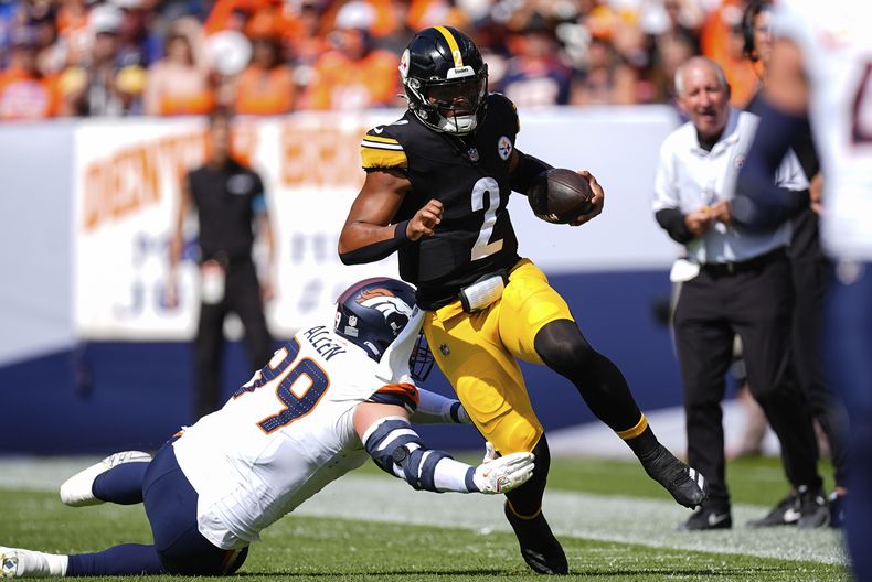 Justin Fields (2), quarterback de los Steelers de Pittsburgh, corre intentando evitar al defensive end Zach Allen (99), de los Broncos de Denver, durante la primera mitad del partido de la NFL, el domingo 15 de septiembre de 2024, en Denver. (AP Foto/David Zalubowski)