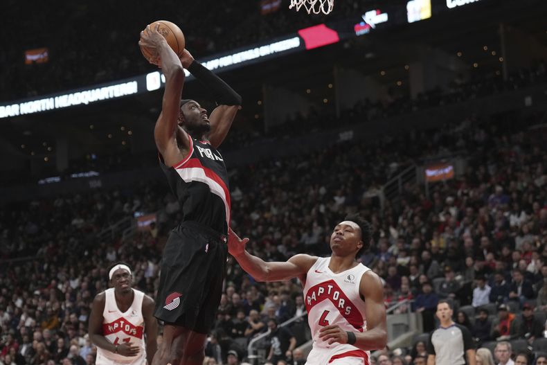 Jerami Grant, arriba, de los Trail Blazers de Portland, clava el balón sobre Scottie Barnes (4), de los Raptors de Toronto, durante la segunda mitad del juego de baloncesto de la NBA, en Toronto, el lunes 30 de octubre de 2023. (Nathan Denette/The Canadian Press vía AP)
