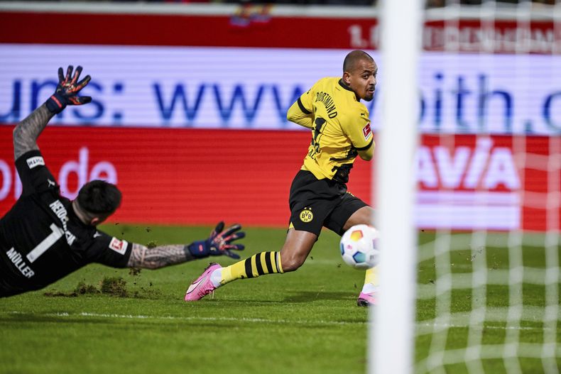 Kevin Mueller, izquierda, portero de Heidenheim, intenta alcanzar un tiro de Donyell Malen, del Dortmund, que acabó en las redes, pero que resultó anulado por un fuera de lugar durante el partido de la Bundesliga de Alemania entre Borussia Dortmund y 1. FC Heidenheim, en la Arena Voith, en Heidenheim, Alemania, el viernes 2 de febrero de 2024. (Harry Langer/dpa vía AP)