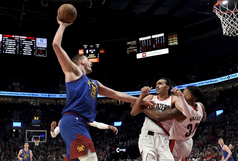 El serbio Nikola Jokic, de los Nuggets de Denver, trata de avanzar frente a Delano Banton (centro) y Jabari Walker, de los Trail Blazers de Portland, el viernes 23 de febrero de 2024 (AP Foto/Steve Dykes)
