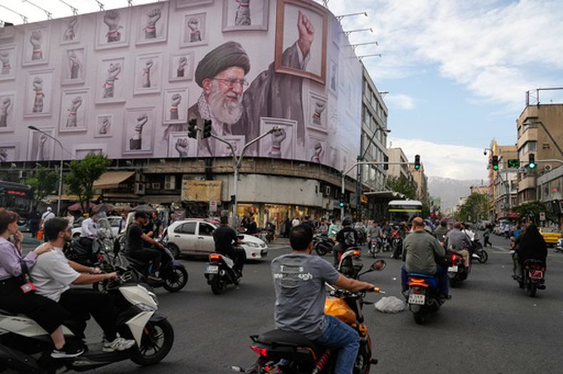 Motocicletas pasan ante un cartel que muestra una imagen del fallecido líder supremo de irán, el ayatolá Alí Jamenei, fallecido en ataques de Estados Unidos e Israel el 28 de febrero, con el puño enmarcado entre puños enmarcados de seguidores, en el centro de Teherán, Irán, el miércoles 6 de mayo de 2026. (AP Foto/Vahid Salemi)