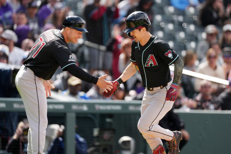 El entrenador de tercera base de los Diamondbacks de Arizona J.R. House felicita a Corbin Carroll mientras rodea las bases tras su jonrón de dos carreras en la cuarta entrada ante los Rockies de Colorado el domingo 17 de mayo del 2026. (AP Foto/David Zalubowski)