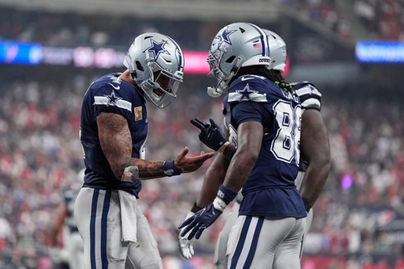 CeeDee Lamb (88) celebra su touchdown con el quarterback Dak Prescott, izquierda, durante la segunda mitad del partido de la NFL en contra de los Texans de Houston, el domingo 4 de octubre de 2026, en Houston. (AP Foto/Ashley Landis)