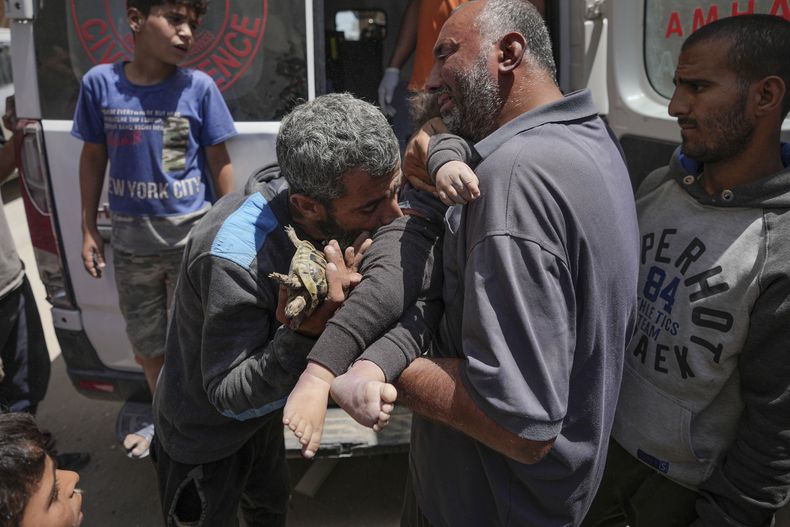 Palestinos sostienen el cuerpo de un bebé muerto rescatado de entre los escombros de un edificio destruido en un ataque aéreo israelí en Nuseirat, en la Franja de Gaza, el 14 de mayo de 2024. (AP Foto/Abdel Kareem Hana)