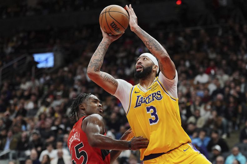 Anthony Davis, de los Lakers de Los Ángeles, dispara frente a Davion Mitchell, de los Raptors de Toronto, en el encuentro del viernes 1 de noviembre de 2024 (Frank Gunn/The Canadian Press via AP)
