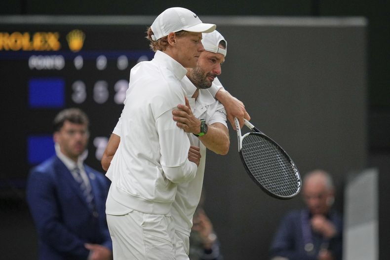 El italiano Jannik Sinner asiste al búlgaro Grigor Dimitrov tras lesionarse en el duelo de cuarta ronda de Wimbledon el lunes 7 de julio del 2025. (AP Foto/Kin Cheung)