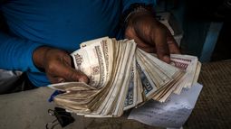 ARCHIVO - Un trabajador muestra un fajo de pesos cubanos el 11 de diciembre de 2020, en La Habana, Cuba. (AP Foto/Ramón Espinosa, Archivo)
