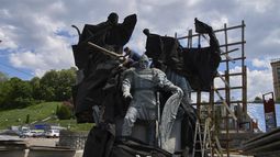 Trabajadores municipales retiran la cobertura que protegía un monumento a los fundadores legendarios de Kiev de ataques de misiles rusos en el cuarto año de la guerra entre Rusia y Ucrania, en la plaza principal de Kiev, Ucrania, el miércoles 21 de mayo de 2025. (AP Foto/Efrem Lukatsky)