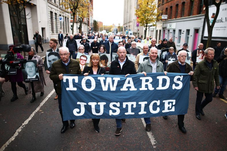 Parientes y defensores de las víctimas de la masacre del Domingo Sangriento de 1972 marchan hacia la Corte de la Corona de Belfast antes del veredicto en el juicio de un soldado británico identificado sólo como Soldado F, en Belfast, en Irlanda del Norte, el jueves 23 de octubre de 2025. (AP Foto/Peter Morrison)
