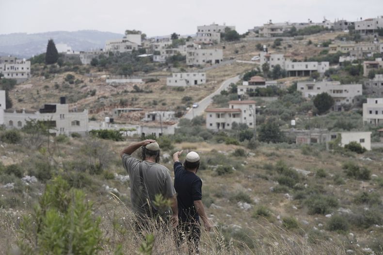 Colonos israelíes miran hacia el pueblo vecino a la mañana siguiente de que Tzeela Gez, que iba camino del hospital para dar a luz, fuera asesinada en un ataque a las afueras del asentamiento de Bruchin, en Cisjordania, el 15 de mayo de 2025. (AP Foto/Maya Alleruzzo)