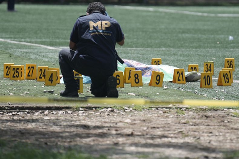 Un investigador del Ministerio Público recaba pruebas junto al cuerpo de Juan Francisco Solórzano Foppa, abogado y exfiscal, en un campo de fútbol tras un tiroteo ocurrido en la Ciudad de Guatemala el sábado 17 de octubre de 2026. (AP Foto/Emmanuel Andres)