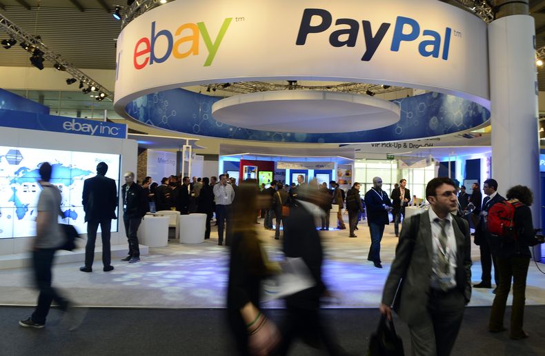 Asistentes al Mobile World Congress, el congreso mundial de tel&eacute;fonos celulares m&aacute;s grande del mundo, pasan debajo de un letrero de eBay y PayPal en Barcelona, Espa&ntilde;a, el 27 de febrero de 2013. PayPal se separar&aacute; de eBay en 201