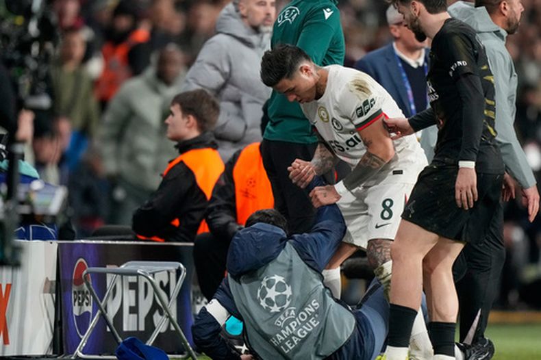 Enzo Fernández, del Chelsea, ayuda a levantarse a un recogebalones después de que su compañero de equipo, el portugués Pedro Neto, lo empujara en su prisa por devolver el balón al terreno de juego, durante el juego de ida de los octavos de final de la Liga de Campeones entre el París Saint-Germain y el Chelsea, en París, el miércoles 11 de marzo de 2026. (Foto AP/Michel Euler)