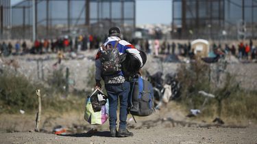 Migrantes carga varias mochilas mientras se dirige hacia la barrera en entrada de la frontera con Estados Unidos desde Ciudad Juárez, México, el 27 de diciembre de 2023. (AP Foto/Christian Chávez)