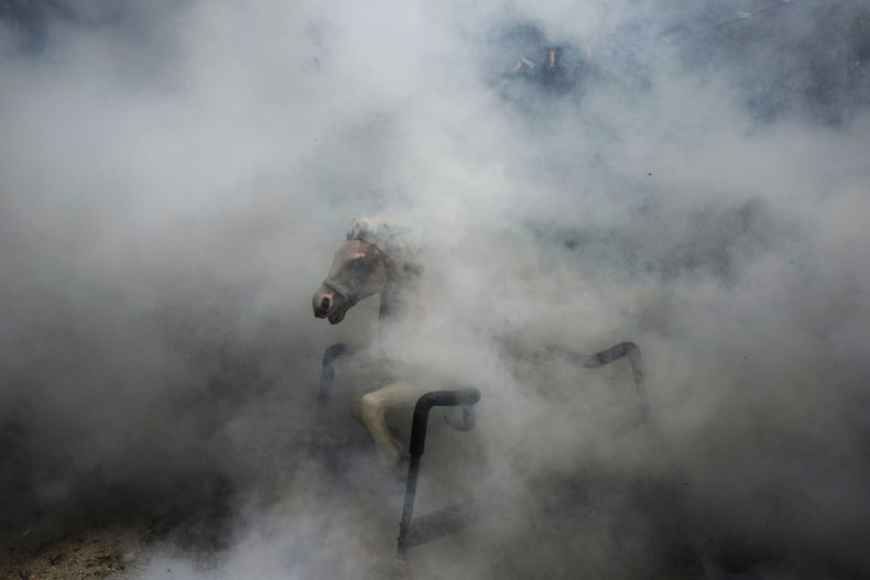 El humo de la fumigación envuelve a un caballo de juguete sentado en una superficie dura mientras los trabajadores de la salud rocían áreas residenciales para matar mosquitos y combatir la propagación del dengue en la Ciudad de Panamá, el miércoles 23 de julio de 2025. (AP Foto/Matías Delacroix)
